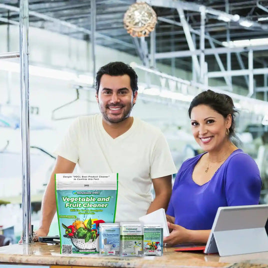 Two people standing behind a counter with various products, including a box labeled 'Vegetable and Fruit Cleaner'.