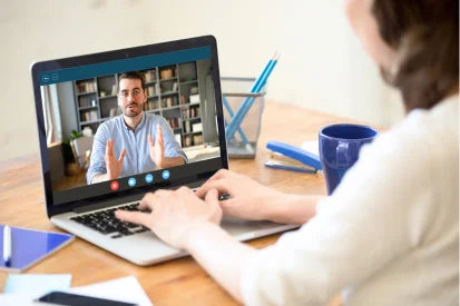 Person on a video call with another person using a laptop at a desk.