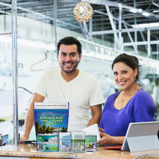 Two people standing behind a counter with various products, including 'Marine & Boat Tank Cleaner'.