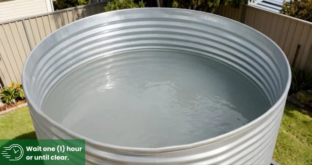 Large metal water tank with water inside, outdoors.