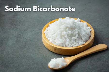 Wooden bowl and spoon filled with sodium bicarbonate on a dark background