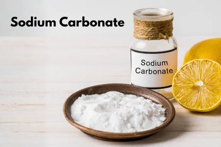 Sodium carbonate with a bottle labeled 'Sodium Carbonate' and a lemon on a light wooden surface.