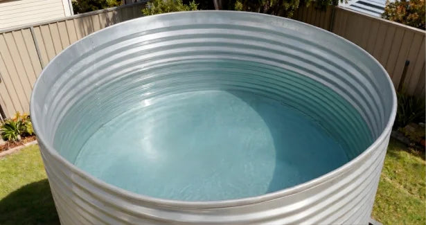 Large cylindrical water storage tank with water inside, outdoors.
